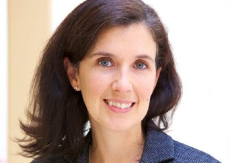 A woman with dark hair wearing a blazer poses for the camera. 