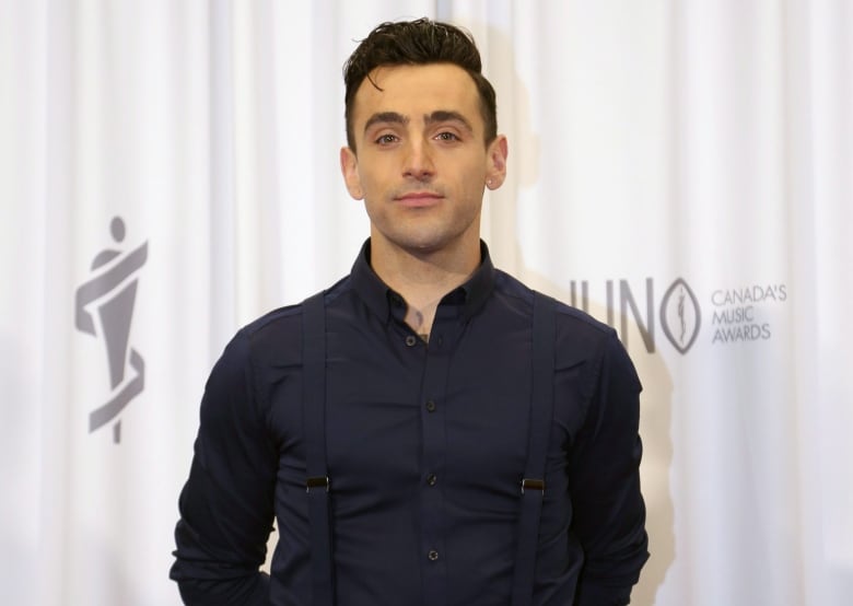 A person stands in front of a backdrop decorated with the Juno awards logo.