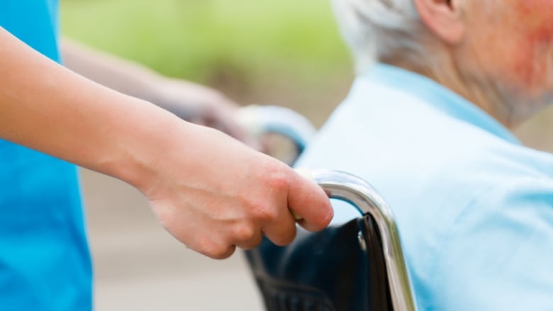 Close up image of a nurse pushing an elderly person in a wheelchair.