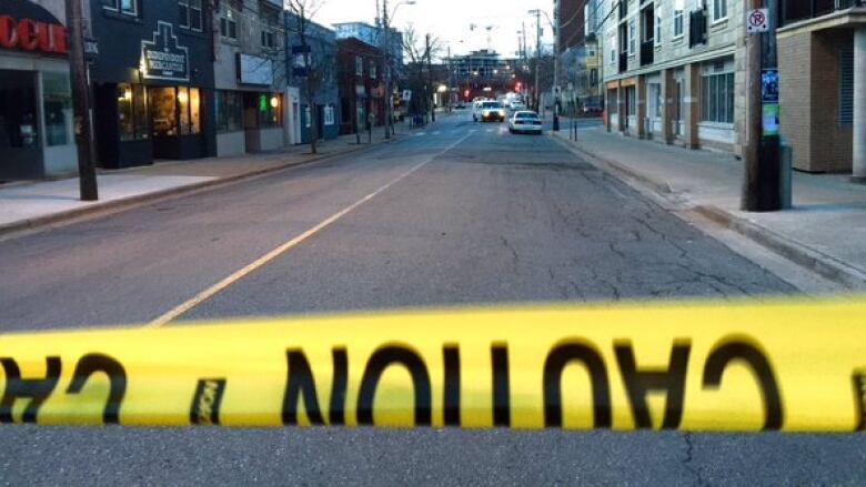 A line of caution tape runs across the bottom of the photo with Gottingen Street, a police car and a crosswalk in the background.