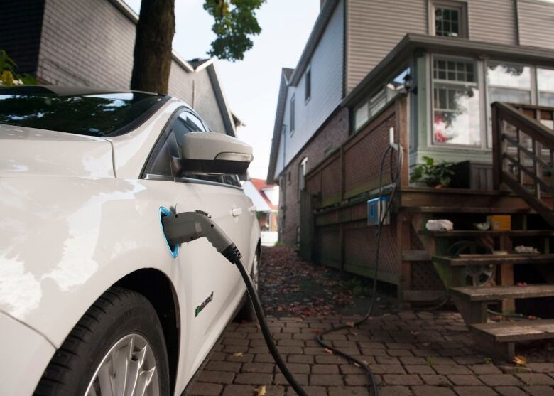 A white electric car charges in a driveway.