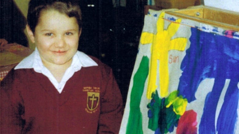 A young boy standing beside a painting