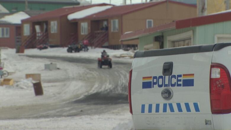 The back of an RCMP truck with snowmobiles on a snowy road. 