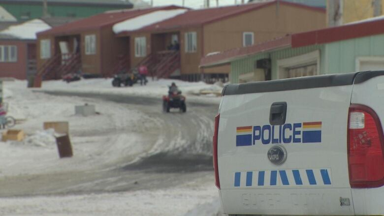 The back of an RCMP truck with snowmobiles on a snowy road. 