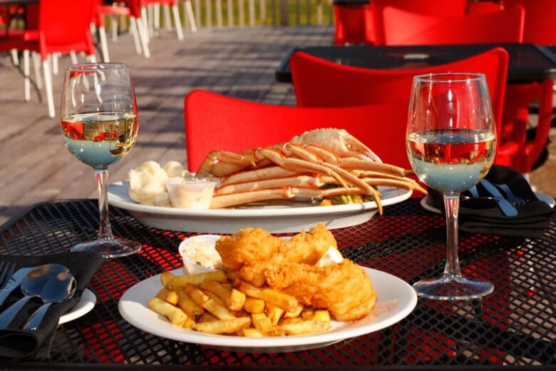 Two plates with seafood and two wine glasses on a restaurant table.