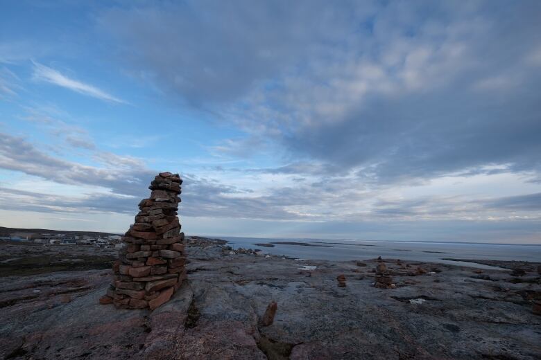 Rock formation, blue sky, buildings in background.