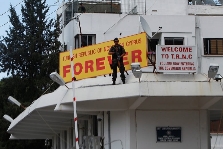 A special police sniper stands guard on the police building by a sign reading 