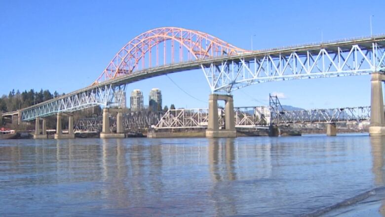 A bridge with orange tresses above a river.