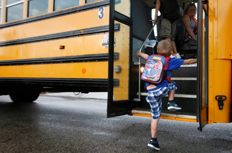 Kid with backpack gets on bus