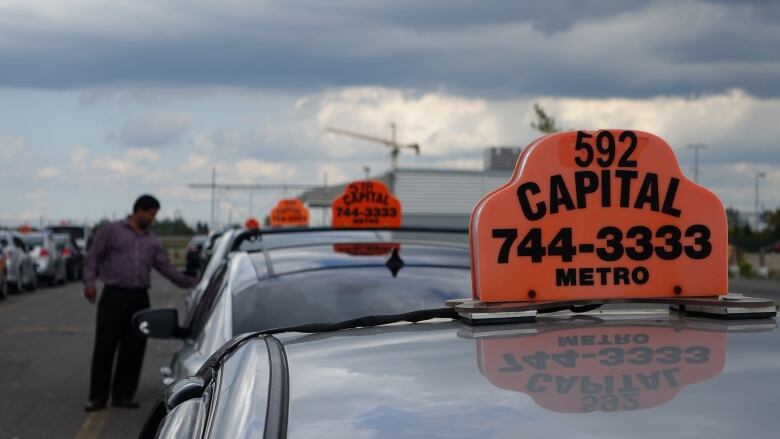 A row of cabs with a driver standing outside