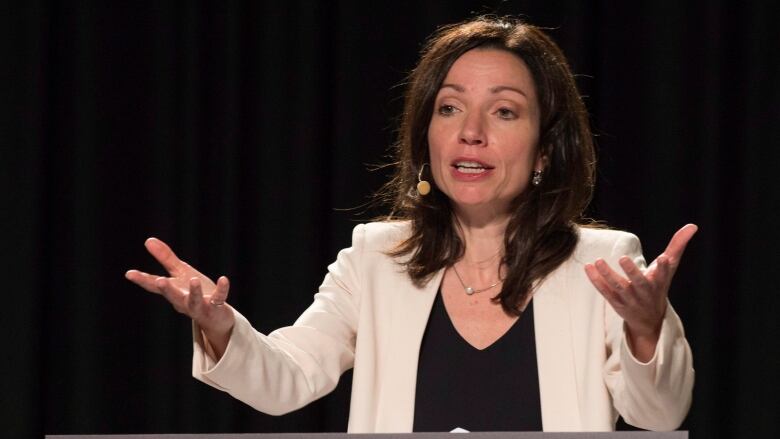 A woman with a microphone attachment gestures.