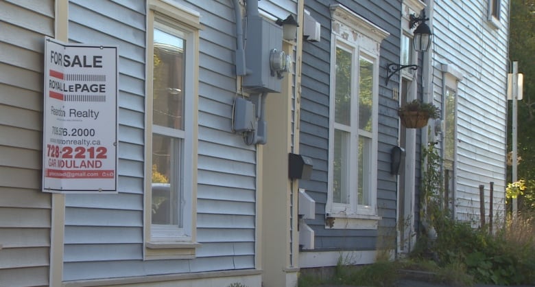 A row of houses with a for sale sign. 