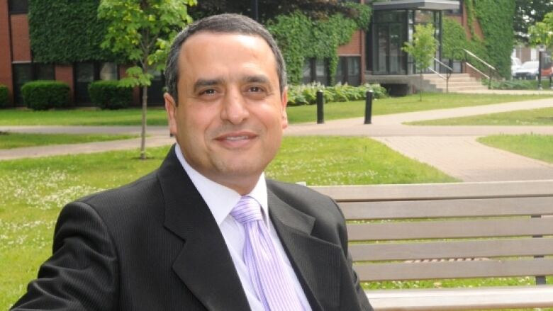 A man in a business suit sits on a bench.