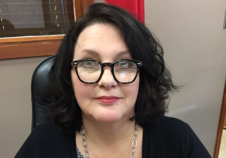 A woman sits in an office, looking toward the camera.