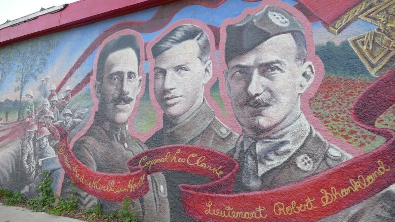 A mural shows the faces of three men in military garb.