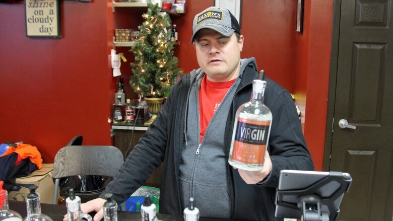 A man holds a bottle of gin. 