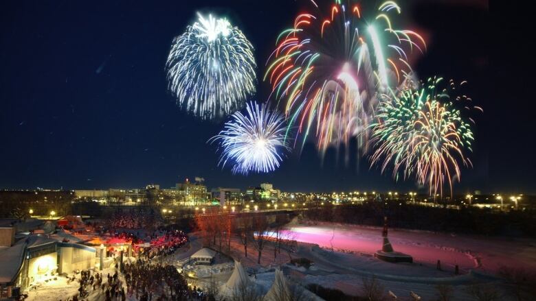 Fireworks explode above city buildings.