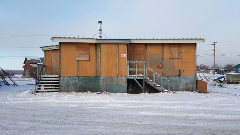 A wooden house sits boarded up in the middle of winter. The house used to be public housing in Behchoko.