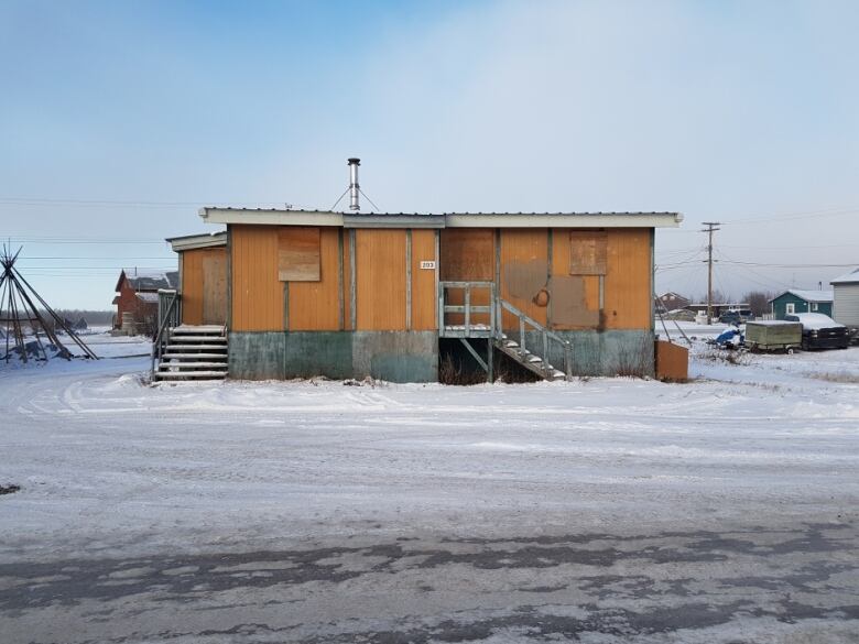 A wooden house sits boarded up in the middle of winter. The house used to be public housing in Behchoko.