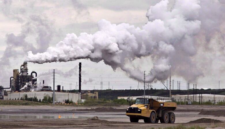 A construction truck is pictured in front of a smokestack.