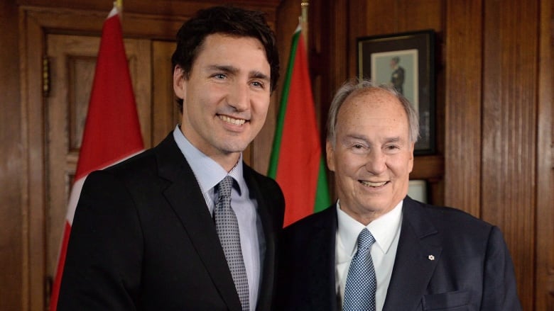 Two men in suits stand and face the camera.