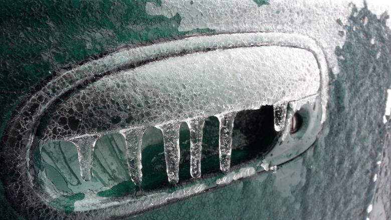 A vehicle's side mirror is shown encased in ice.