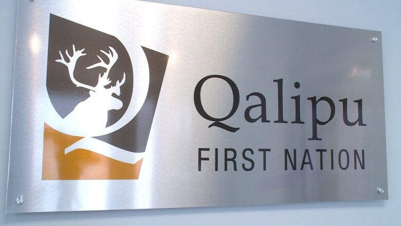 A metal sign with a logo featuring a Q and the silhouette of a caribou and the words Qalipu First Nation.