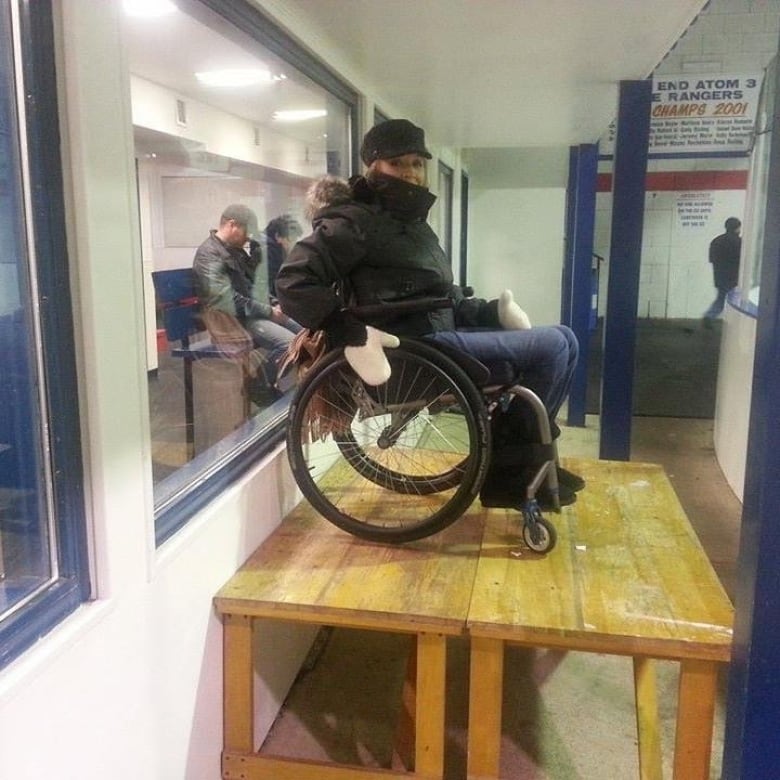 A woman in a black coat sits on a wheelchair.