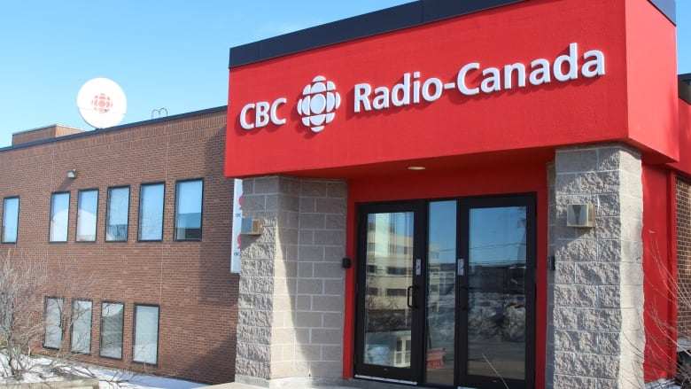 A building with a red sign with CBC Radio-Canada in white on the front of the brick building.