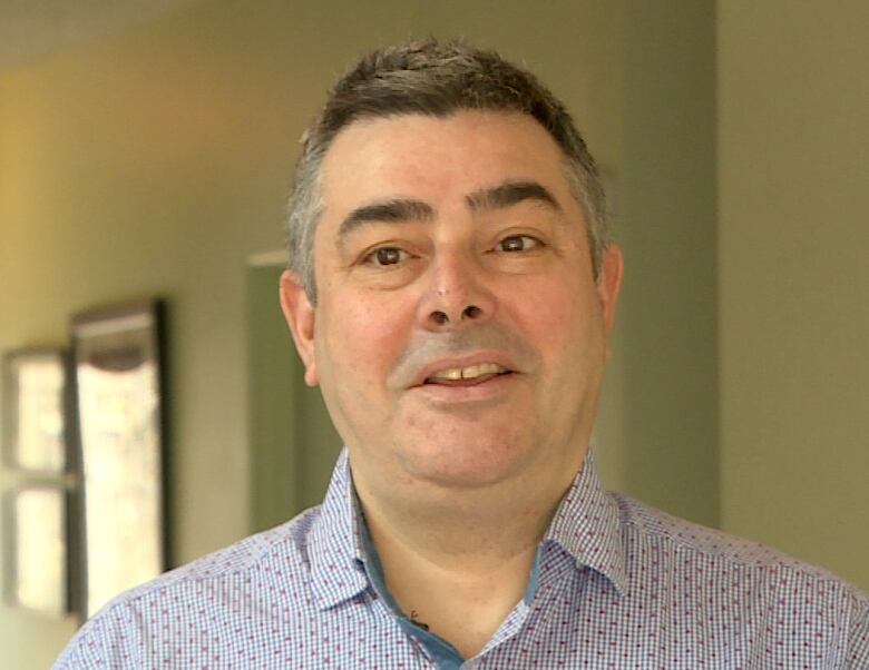 A man with salt and pepper hair looks into the camera. 