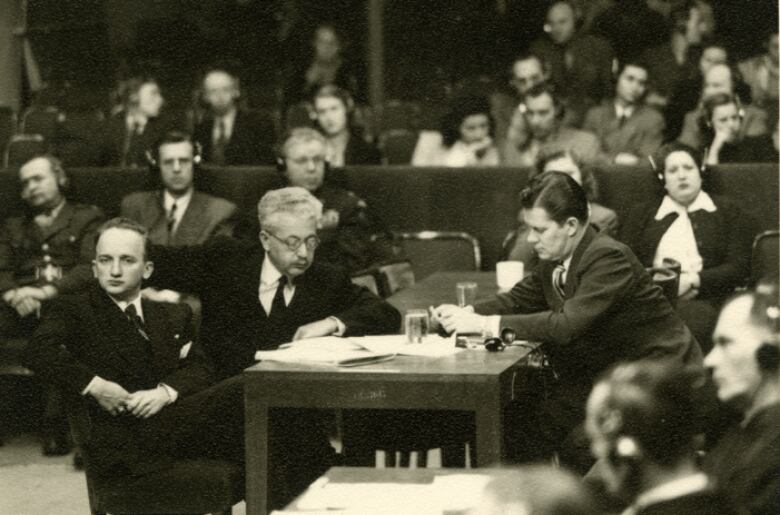 People in suits are seen sitting inside a courtroom in this photo from the 1940's.