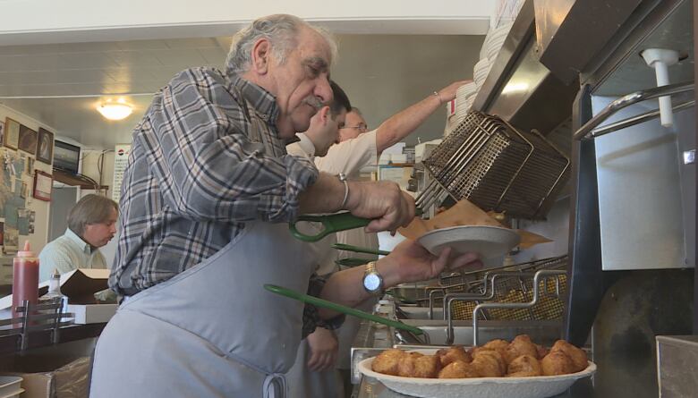 Fotis Fatouros scoops food out of a deep fryer at Pleasant St. Diner.