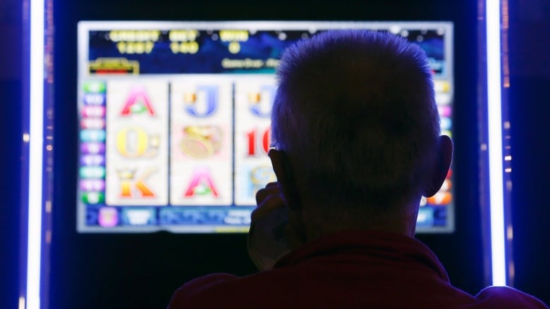 a man's head is silhouettedin the light of a VLT machine 