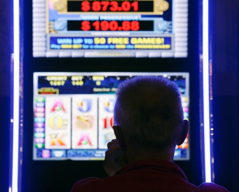 a man's head is silhouettedin the light of a VLT machine 