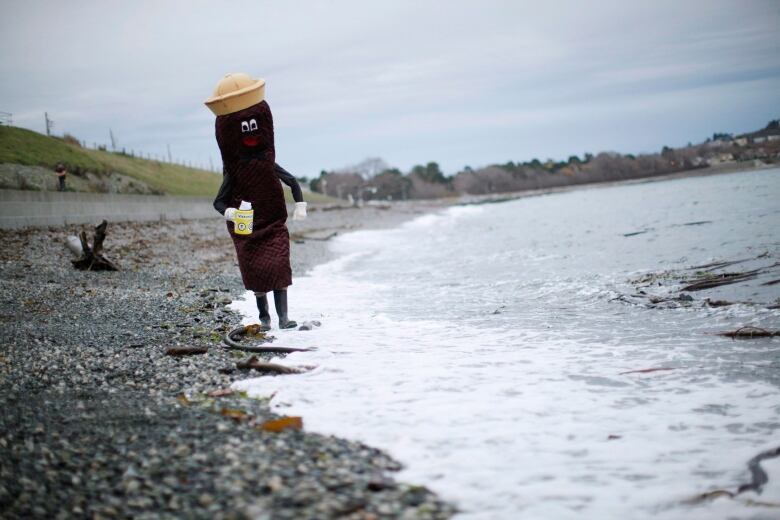 A person in a costume that looks like a cartoon piece of feces walks in the ocean.