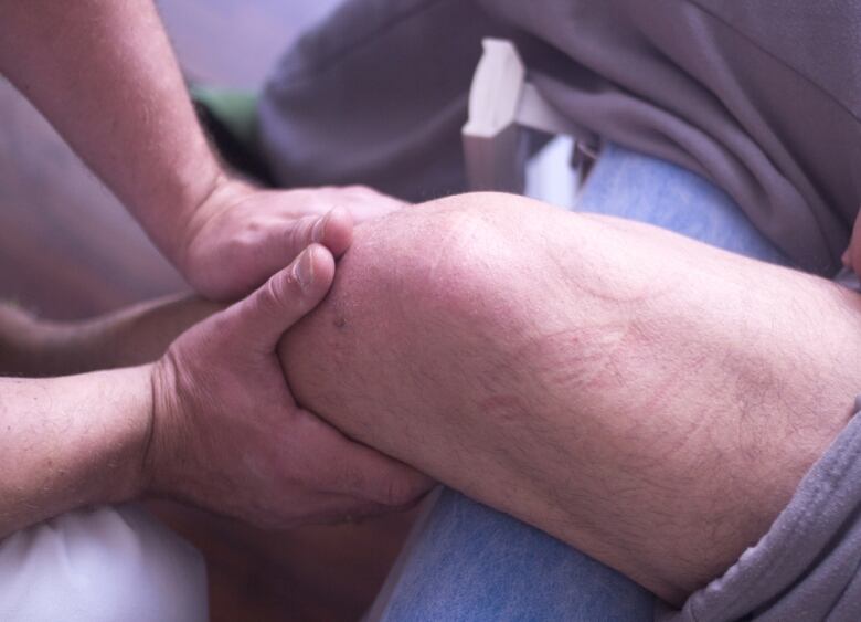 A pair of hands massage another person's leg.