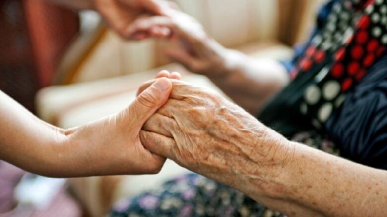 A younger pair of hands holding an older pair of hands.