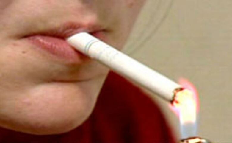 A woman lights a cigarette.