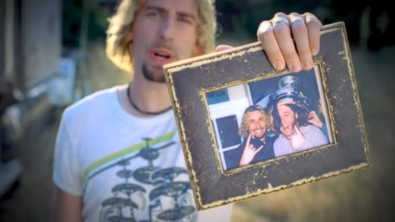 Singer Chad Kroeger holds a photograph of himself as a younger man with a young woman, in an image from Nickelback's music video for the song Photograph.