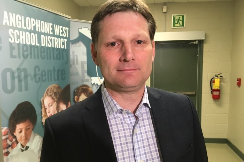 A man with short brown hair wearing a black suit jacket