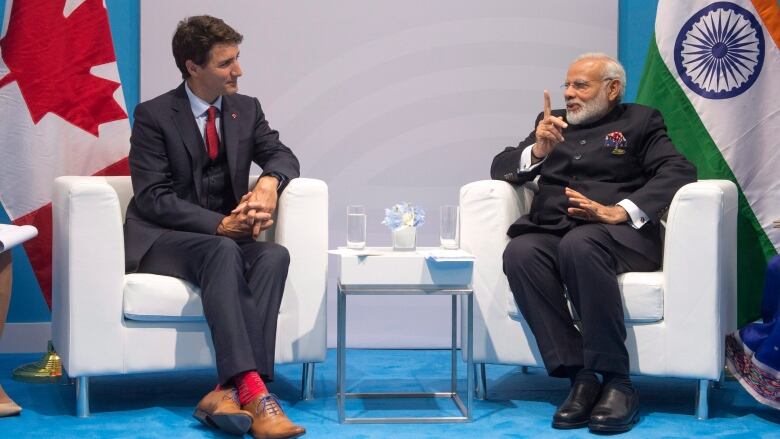 Two men sit talking to one another.