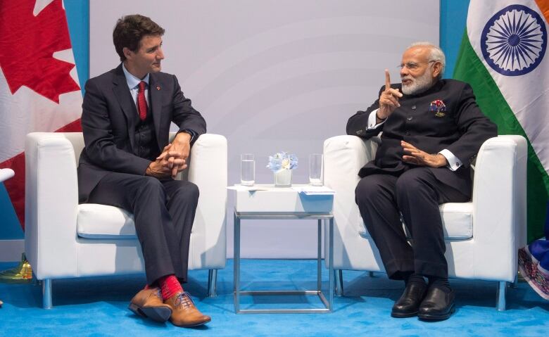 Two men sit talking to one another.