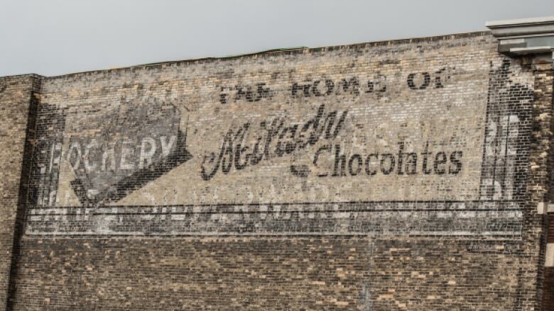 A faded, painted sign on the side of a brick building