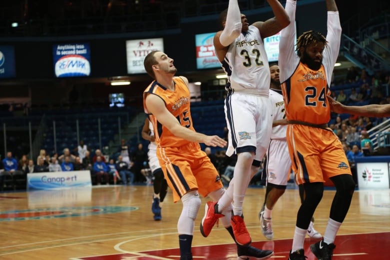 Three basketball players under the hoop during a game