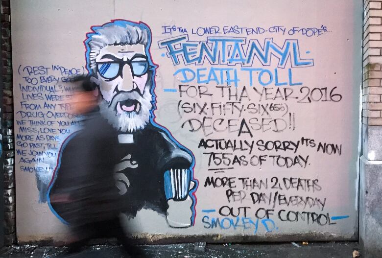 A man walking past a mural.