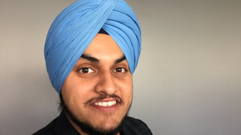 A man wearing a blue turban smiles.