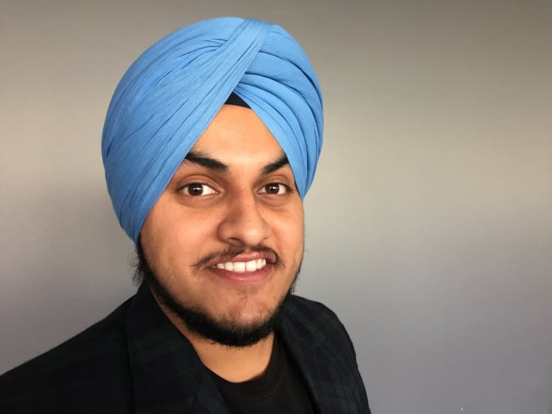 A man wearing a blue turban smiles.