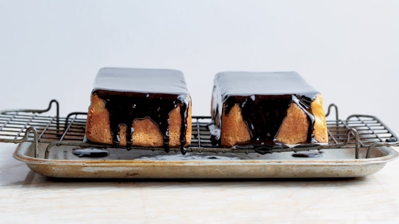 2 small cakes on a cooling rack, drizzled with chocolate ganache