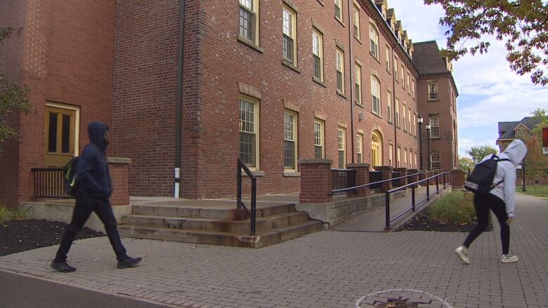 Two students walking in front of the main building on the UPEI campus.