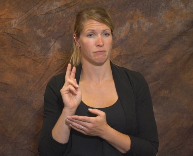 A woman signing in ASL with her two hands.